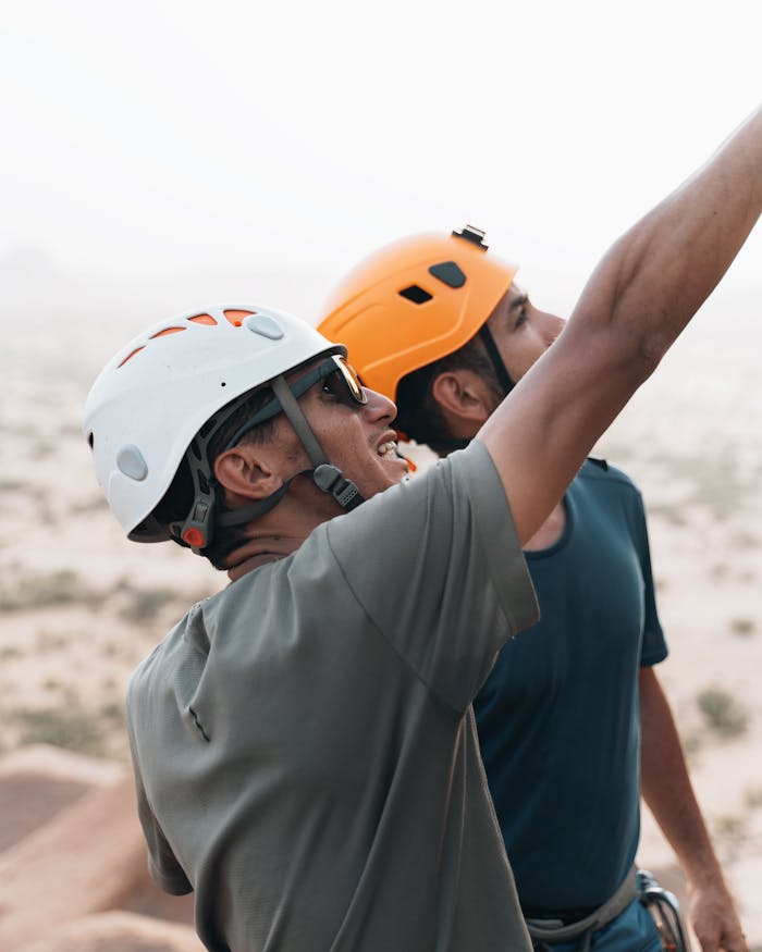 portfolio-02 Two male climbers wearing helmets and pointing during an outdoor adventure.