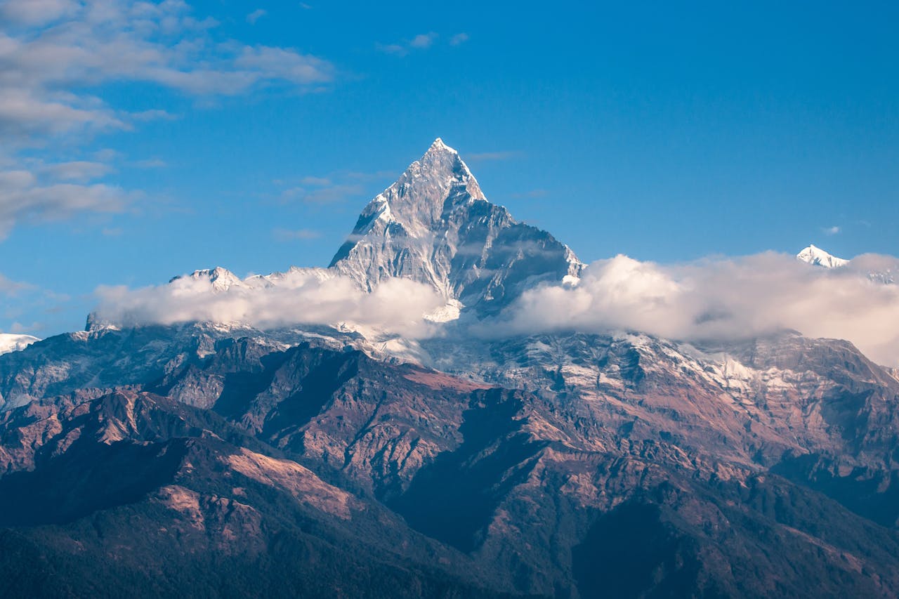 gallery-01 Breathtaking view of a snow-covered mountain peak surrounded by clouds during sunrise.